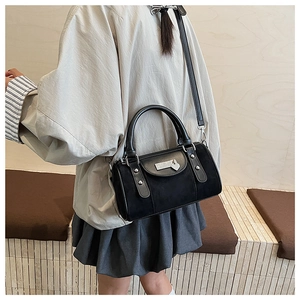Détail du sac Boston en daim noir avec pendentif en cœur et rivets métalliques fins