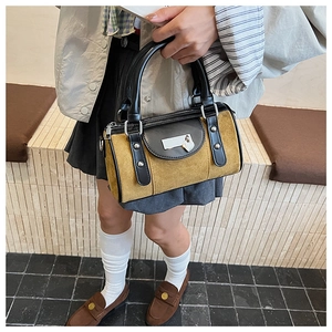 Gros plan du sac Boston en daim avec pendentif cœur et détails de clous métalliques