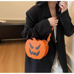 Close-up of orange pumpkin crossbody bag with black face and golden hardware