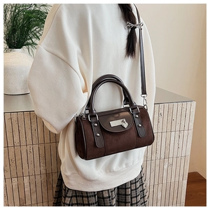 Détail du sac seau cylindrique marron vintage avec breloque cœur et finitions métalliques