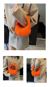 Detail of bright orange quilted puffer hobo bag with grid stitching and soft cloud texture