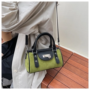 Détail du sac Boston en daim vert olive avec sangles en cuir noir et rivets argentés