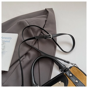 Détail du sac Boston en daim avec surpiqûres contrastées et pendentif en forme de cœur