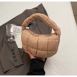 Close-up of khaki quilted puffy handbag with thick handle and silver zipper detail