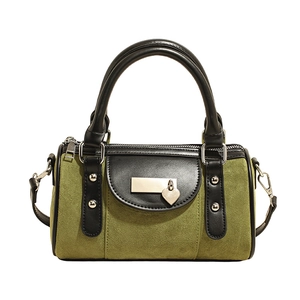 Détail du sac Boston en daim vert avec pendentif coeur et finitions en cuir noir