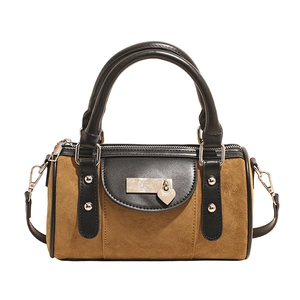 Détail du sac Boston en daim avec contraste caramel et noir et breloque coeur en métal