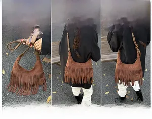 Détail macro du sac bandoulière en daim marron avec franges vintage et styles de porté