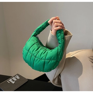 Detailed shot of a bright green quilted crescent handbag with puffer padded handle