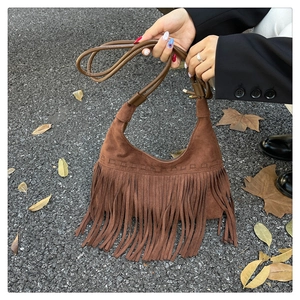 Gros plan d'un sac bandoulière vintage en daim marron avec de longues franges à franges