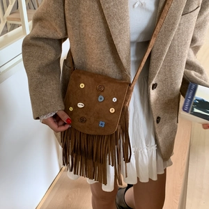 Bohemian brown suede crossbody bag with vintage fringe and shell details on a model