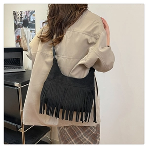 Détail d'un sac bandoulière vintage en daim noir avec de longues franges sur modèle
