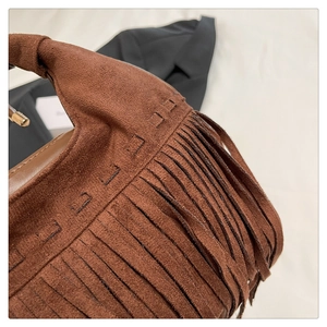 Gros plan sur un sac en daim marron vintage avec coutures faites main et longues franges