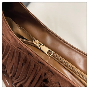 Détail de la fermeture éclair dorée sur le sac à main marron en daim avec franges