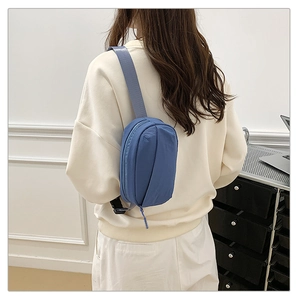 Rear view of a model wearing a lightweight blue-purple sporty nylon crossbody chest bag