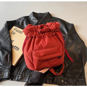 Macro detail of red nylon bucket bag showing drawstring closure and front pocket