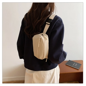 Detail of minimalist cream nylon crossbody bag with adjustable strap and plastic buckle