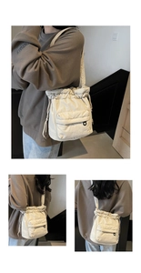 Detail of a beige nylon bucket bag featuring drawstring closure and front flap pocket