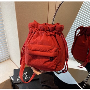 Detail of red nylon bucket bag with drawstring closure and texture in soft indoor light