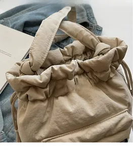 Macro shot of beige quilted nylon bucket bag with drawstring closure and knotted handle