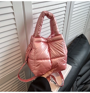 Detail of a pink metallic quilted puffer handbag featuring a glossy padded lattice texture
