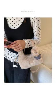 Detail der flauschigen cremefarbenen Handtasche mit Bärenanhänger und Ledergurt
