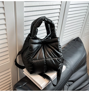 Detailed view of black quilted down handbag with glossy finish and detachable shoulder strap