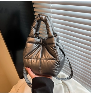 Macro detail of quilted puffer texture on metallic dark grey handbag with stitching