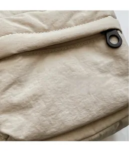 Macro view of beige nylon crossbody bag featuring drawstring texture and zipper detail