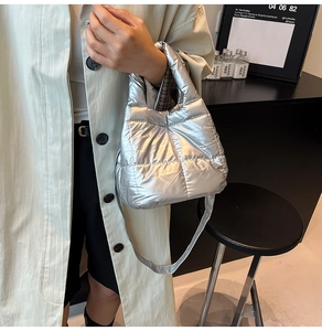 Close-up of silver quilted puffer handbag with metallic finish and crossbody strap