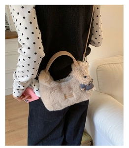Detail einer beigen Plüschhandtasche mit Lederetikett und süßem Teddybär-Anhänger