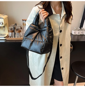 Detail of a black quilted puffer bag with a plush texture and versatile shoulder strap