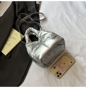 Close-up of metallic silver quilted puffer crossbody bag with dual strap detail