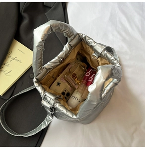 Detailed interior view of silver quilted puffer bag showing space for phone and makeup