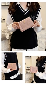 Detail view of pink crocodile embossed wallet with golden flower buckle and wrist strap