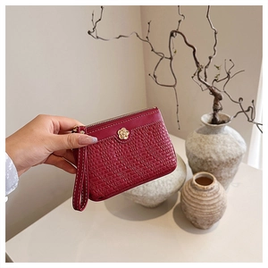 Detailed shot of burgundy short wallet with camellia charm and textured leather finish