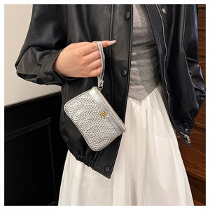 Detailed view of silver woven mini wallet with golden flower badge and wrist strap