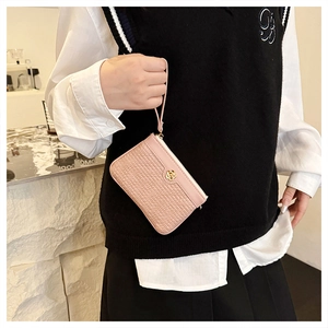 Detail of pink faux crocodile leather coin purse with golden rose emblem and wrist strap