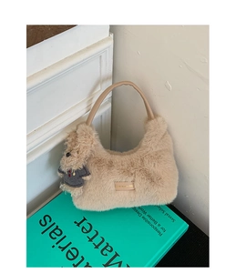 Detailansicht der beigen Plüsch-Hobo-Tasche mit Ledergriff und süßem Bärenanhänger
