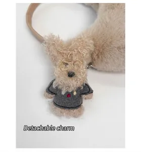 Detail eines abnehmbaren Plüsch-Hundeanhängers mit Mini-Pullover auf der Tasche