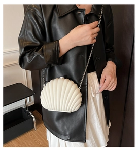 Close-up of a creative shell-shaped clutch bag with striped texture and chain strap