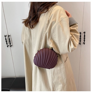 Detail of a purple shell-shaped acrylic clutch with gold chain and 3D textured patterns