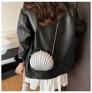 Silver shell-shaped clutch bag with wavy texture on black leather jacket outfit