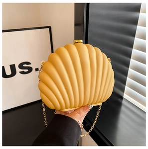 Macro detail of yellow seashell clutch with gold chain strap and textured resin finish
