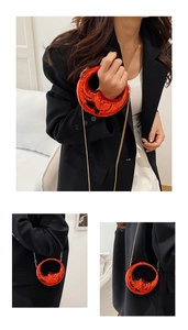 Detail of red moon-shaped metallic handbag with embossed texture and gold chain strap
