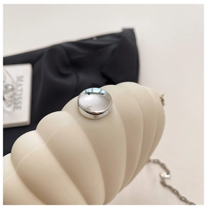 Close-up of cream acrylic shell clutch featuring silver ball clasp and metal chain strap