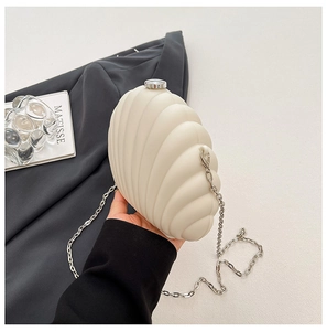 Detail view of cream shell-shaped acrylic clutch bag with silver chain strap