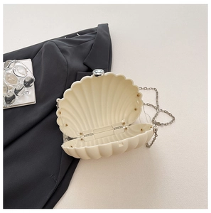 Detail of shell-shaped crossbody bag featuring matte texture and delicate metal chain strap