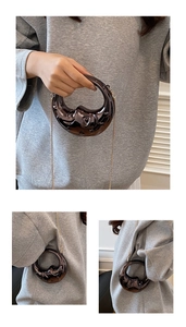 Detail view of crescent handbag with embossed pattern and detachable chain strap