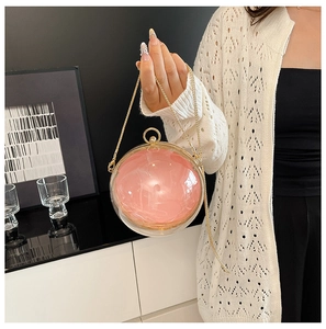 Dettaglio borsa da sera tonda in acrilico rosa con catena dorata tenuta da una donna