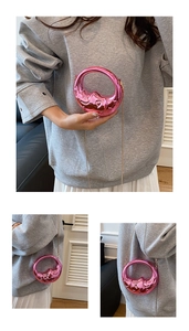 Detail of pink moon-shaped mini evening bag showing metallic texture and gold chain strap